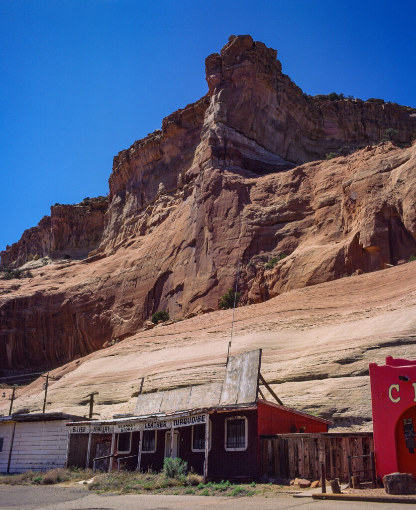 Historic roadside structure and desert architecture near Lupton, Arizona, framed by towering sandstone cliffs in the American Southwest.