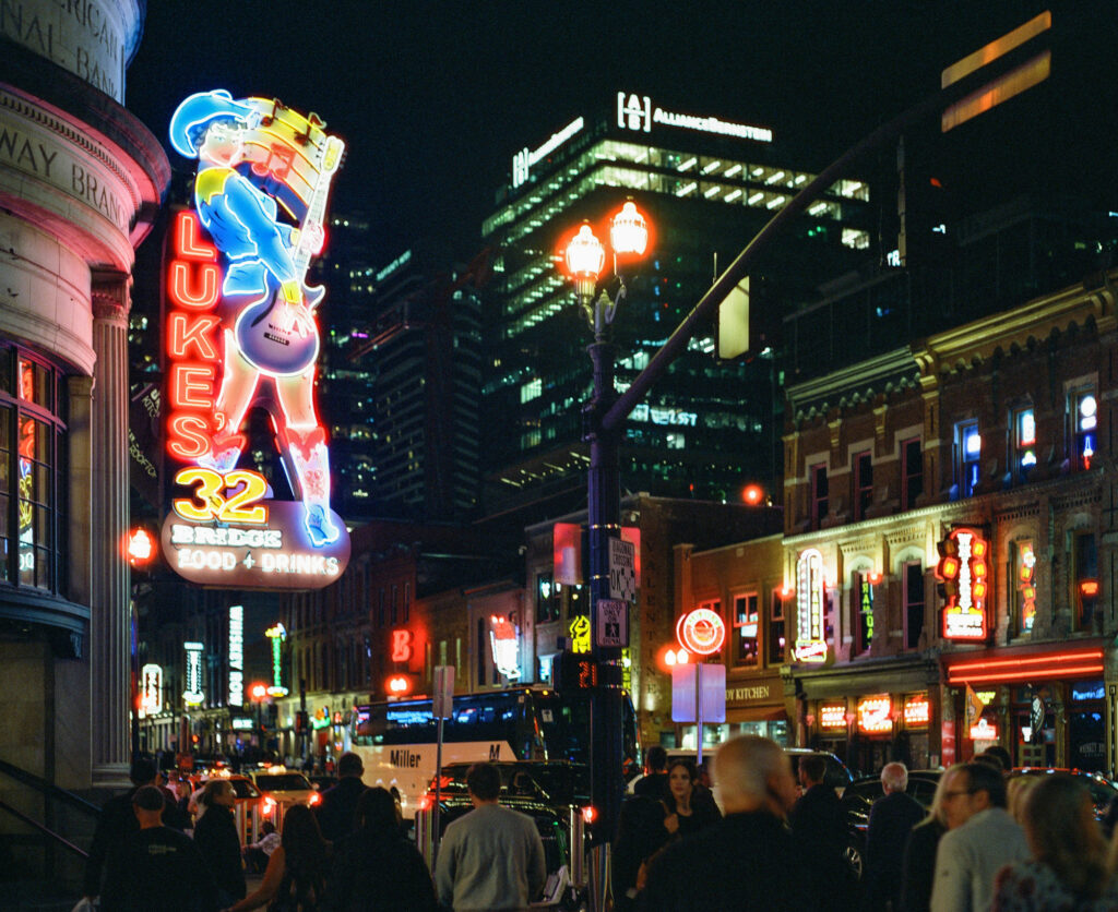 Luke's 32 Bridge Food + Drink neon sign glowing above Lower Broadway in downtown Nashville, photographed at night on a Pentax 67 using CineStill 800T medium format film.