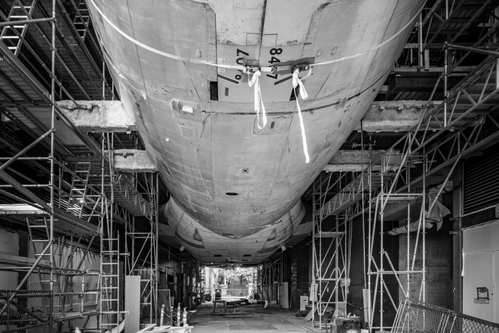 Underside view of the Boeing 747 fuselage suspended between buildings during construction at Aero1200 in Seattle.